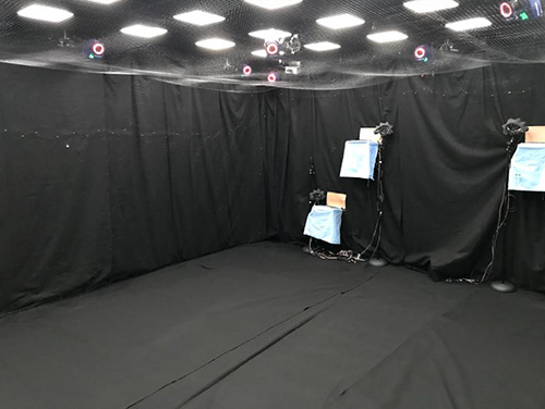 Room walls draped in black fabric, netting on ceiling and sensors